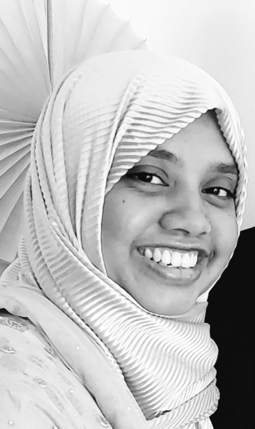 A black and white picture of Rumena Aktar wearing a hijab and smiling.